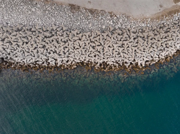 An aerial view of a rocky shore beside deep blue water