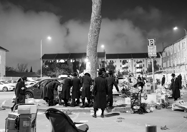 A nighttime gathering beside street signs and stalls