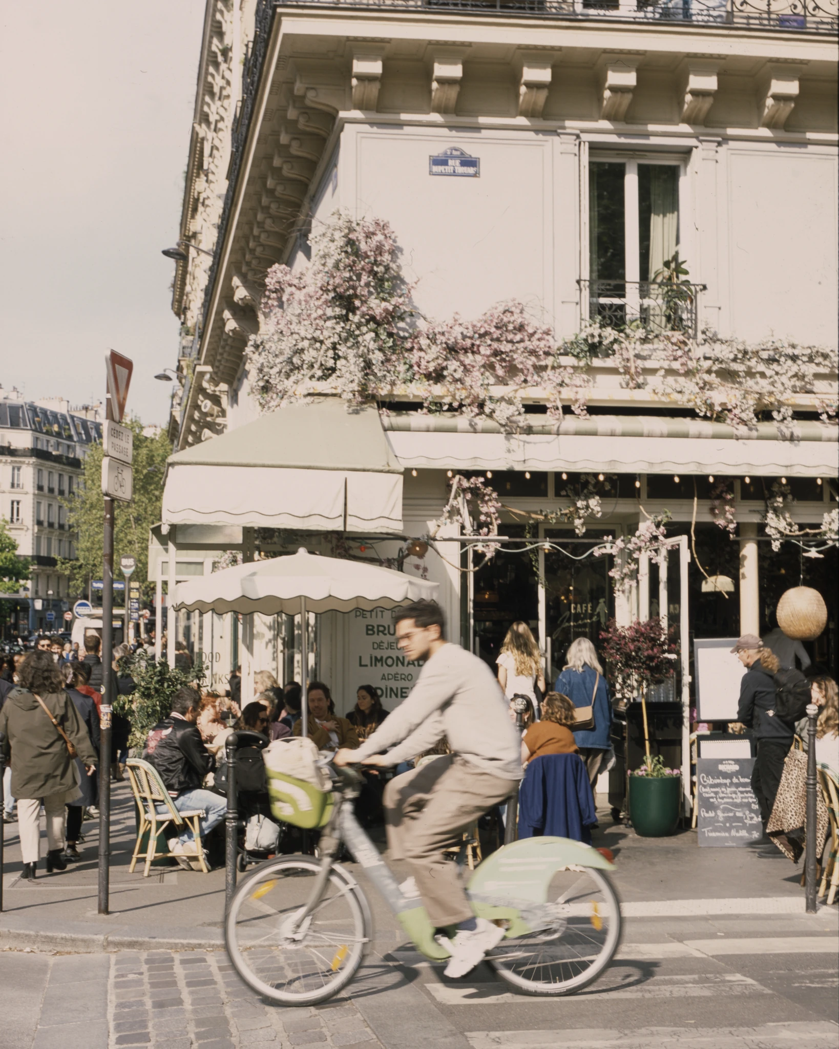 A cyclist passing pedestrians at a city cafe