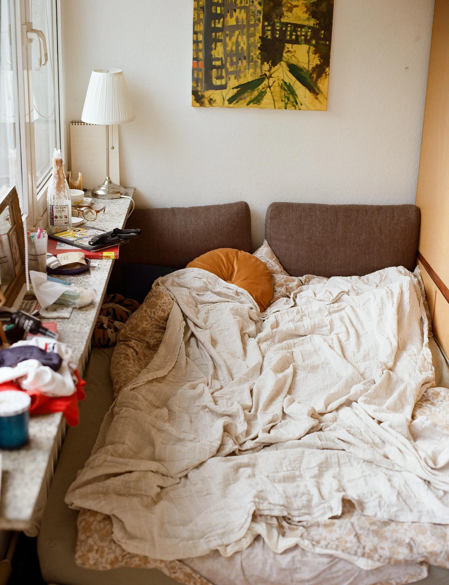 An unmade bed in a softly lit room