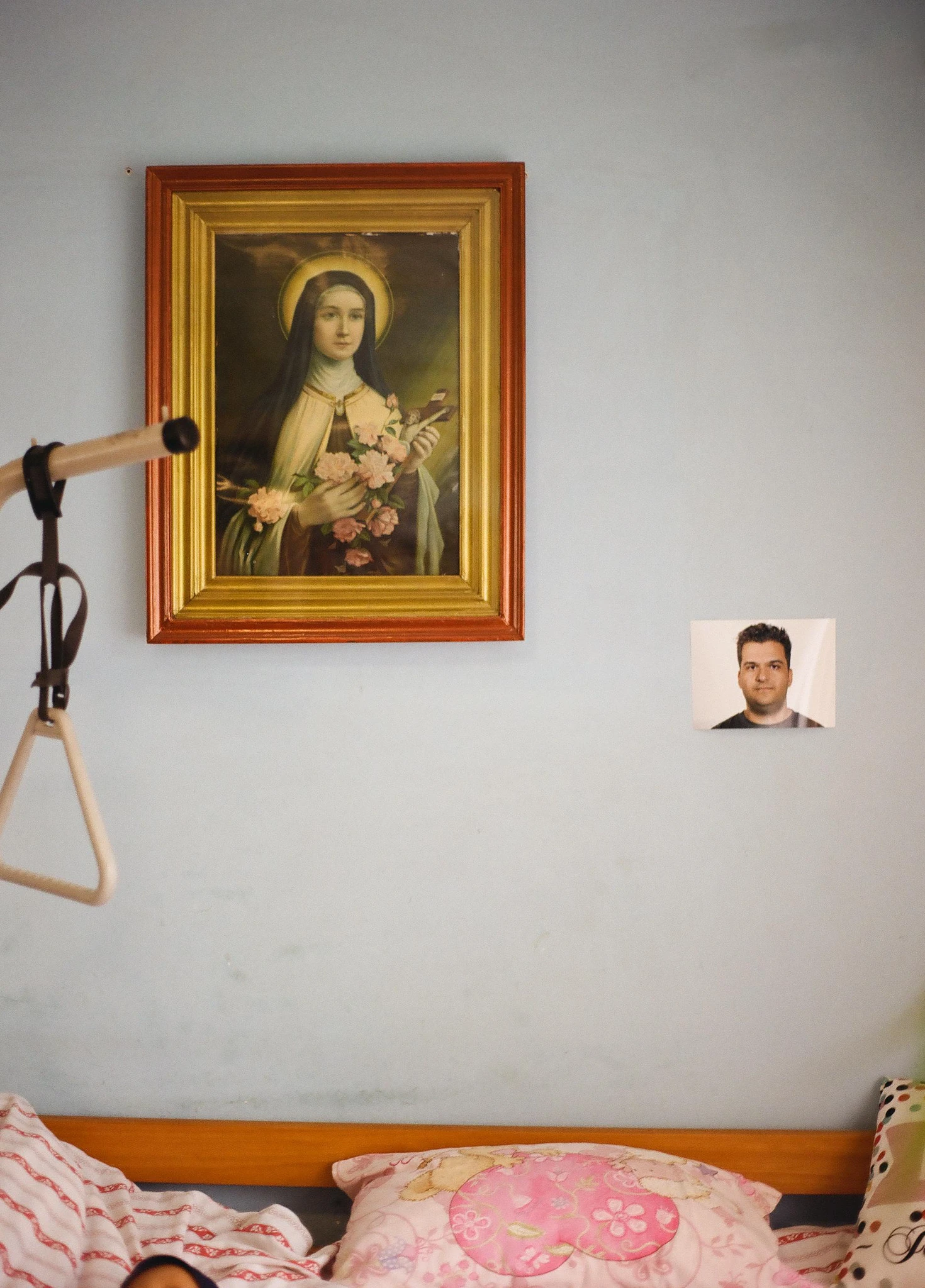 A bedroom wall with a framed religious painting