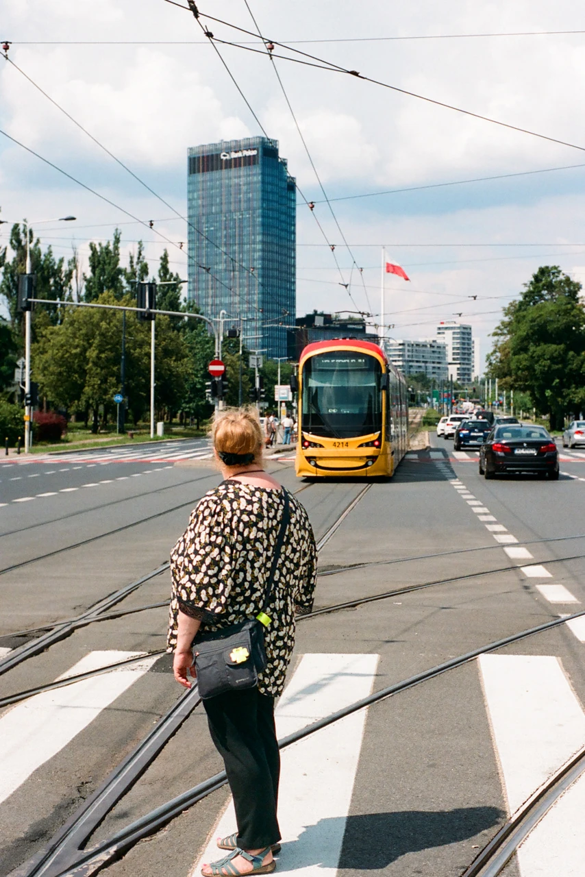 A pedestrian crossing the street in front of a yellow tram